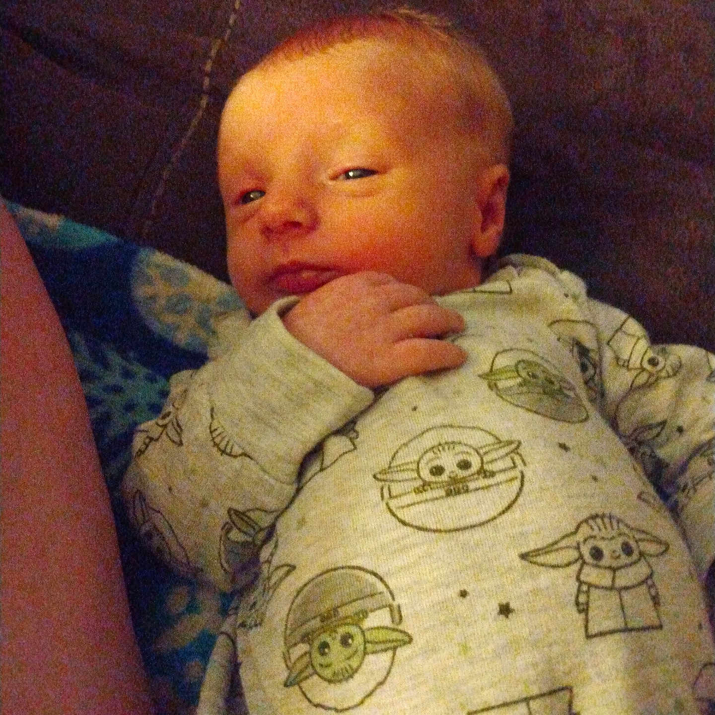 Jesson joined the competition — help win amazing prizes! baby, baby_yoda, child, clothing, couch, curious, cute, face, hand, home, indoors, infant, onesie, person, portrait, relaxed, sleepy, soft_lighting, star_wars, young