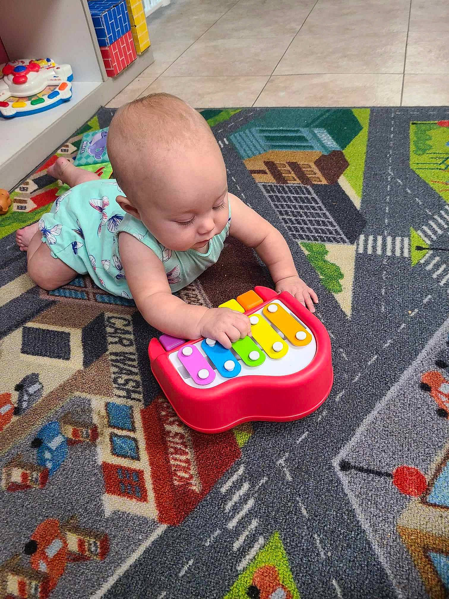 Emery is registered to the contest to win money with this photo: baby, baby_playing_with_toys, baby_products, baby_toddler_clothing, baby_toys, child, floor, flooring, fun, grass, leisure, pattern, person, play, product, room, sitting, toddler, toy, toy_vehicle