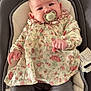 baby, baby_chair, child, clothing, comfort, cushion, cute, expression, face, floral_dress, hands, indoor, infant, pacifier, pants, person, portrait, seated, soft_lighting, young_child