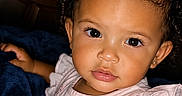 Aria is registered to the contest to win money with this photo: child, toddler, girl, portrait, smiling, curly_hair, hair_bow, pink_dress, baby, sitting, indoors, blanket, couch, basket, brown_eyes, earring, fashion, close_up, family_photo, adorable