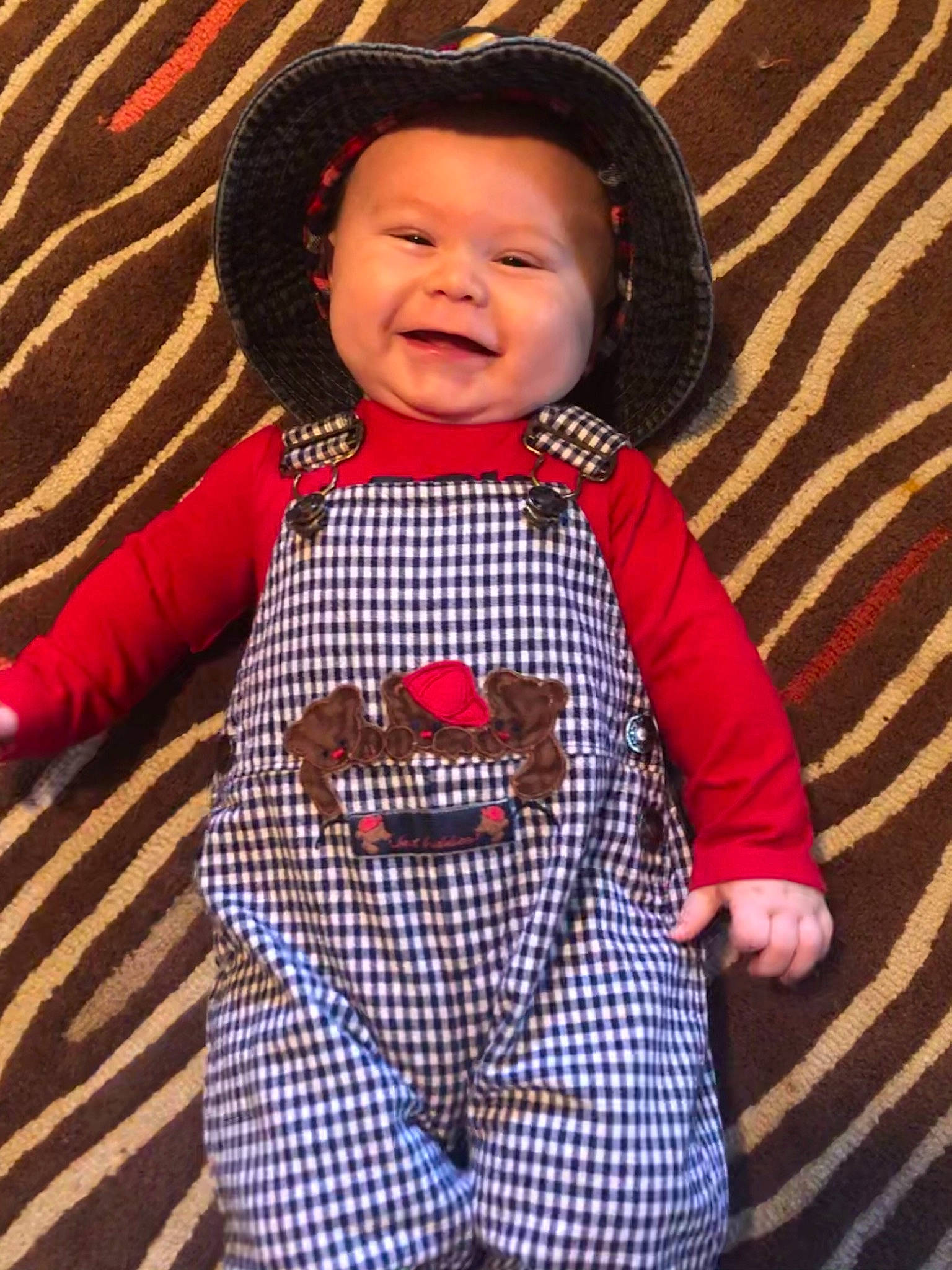 Caney joined the competition — help win amazing prizes! arm, baby, baby_toddler_clothing, finger, flooring, hairstyle, hand, happy, hat, headwear, nose, orange, outerwear, pattern, person, plaid, sleeve, smile, t_shirt, tartan