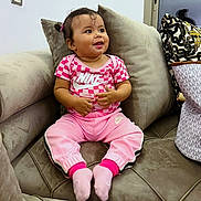 Neila participe au concours pour gagner de l'argent avec cette photo : toddler, child, smile, pink_clothing, nike, socks, couch, pillow, indoor, happy, person, hair_tie, bag, pattern, sitting, furniture, casual, cute, young_child, portrait
