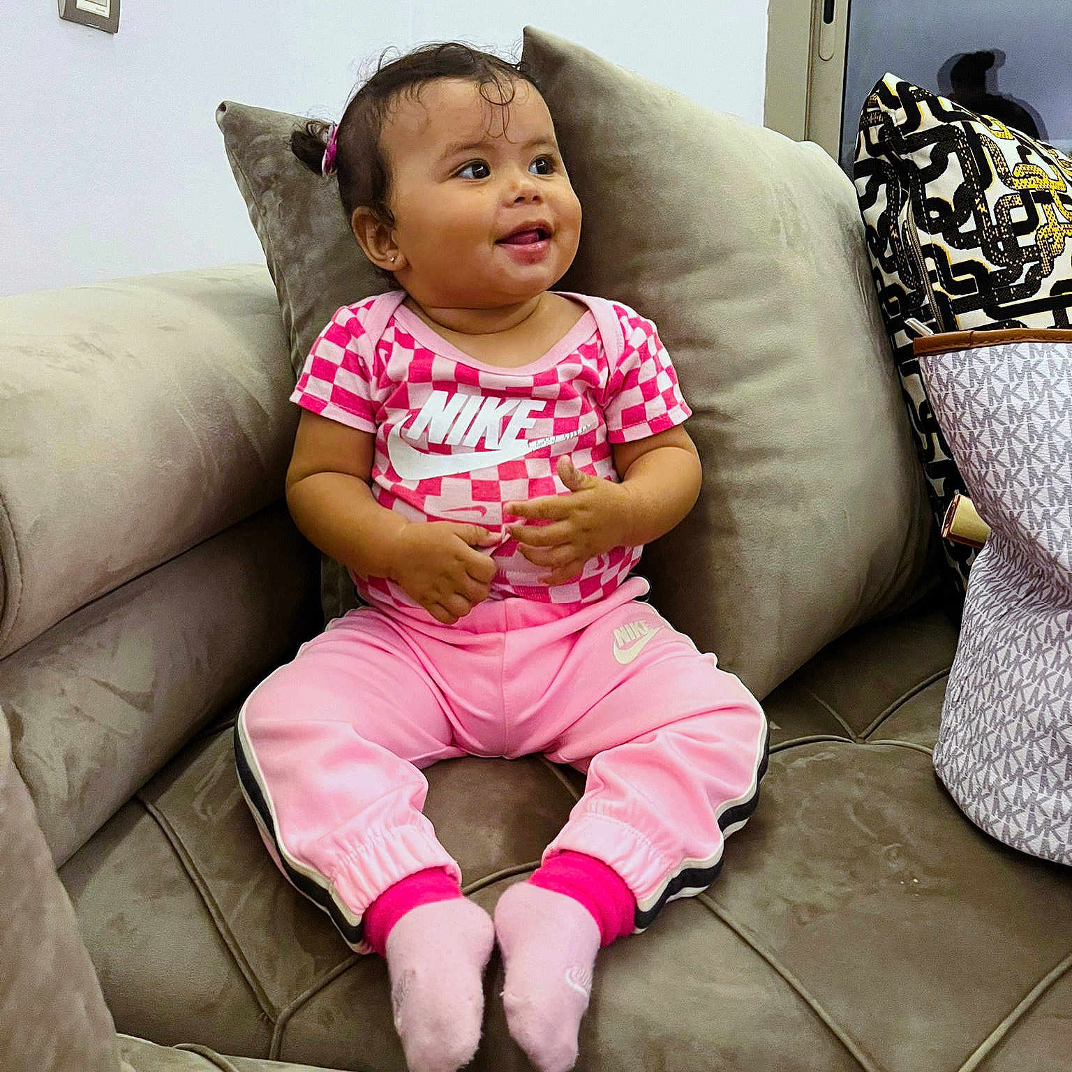 Neila participe au concours pour gagner de l'argent avec cette photo : bag, casual, child, couch, cute, furniture, hair_tie, happy, indoor, nike, pattern, person, pillow, pink_clothing, portrait, sitting, smile, socks, toddler, young_child