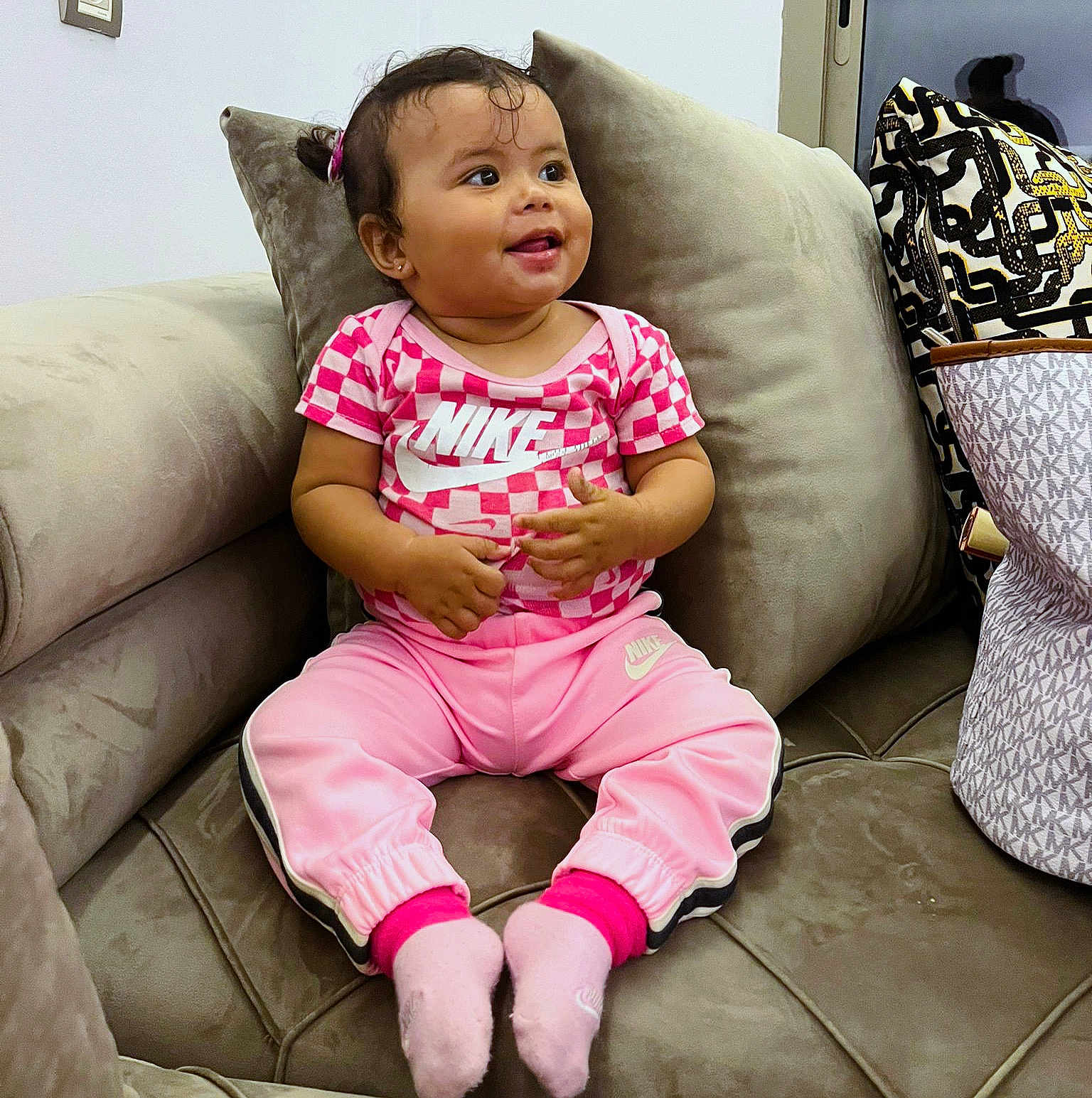 Neila participe au concours pour gagner de l'argent avec cette photo : toddler, child, smile, pink_clothing, nike, socks, couch, pillow, indoor, happy, person, hair_tie, bag, pattern, sitting, furniture, casual, cute, young_child, portrait