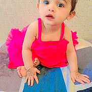 Hezal is registered to the contest to win money with this photo: baby, child, pink_dress, carpet, indoor, curious, sitting, hands, face, eyes, hair, bracelet, foot, portrait, candid, cute, infant, young_child, expression, floor