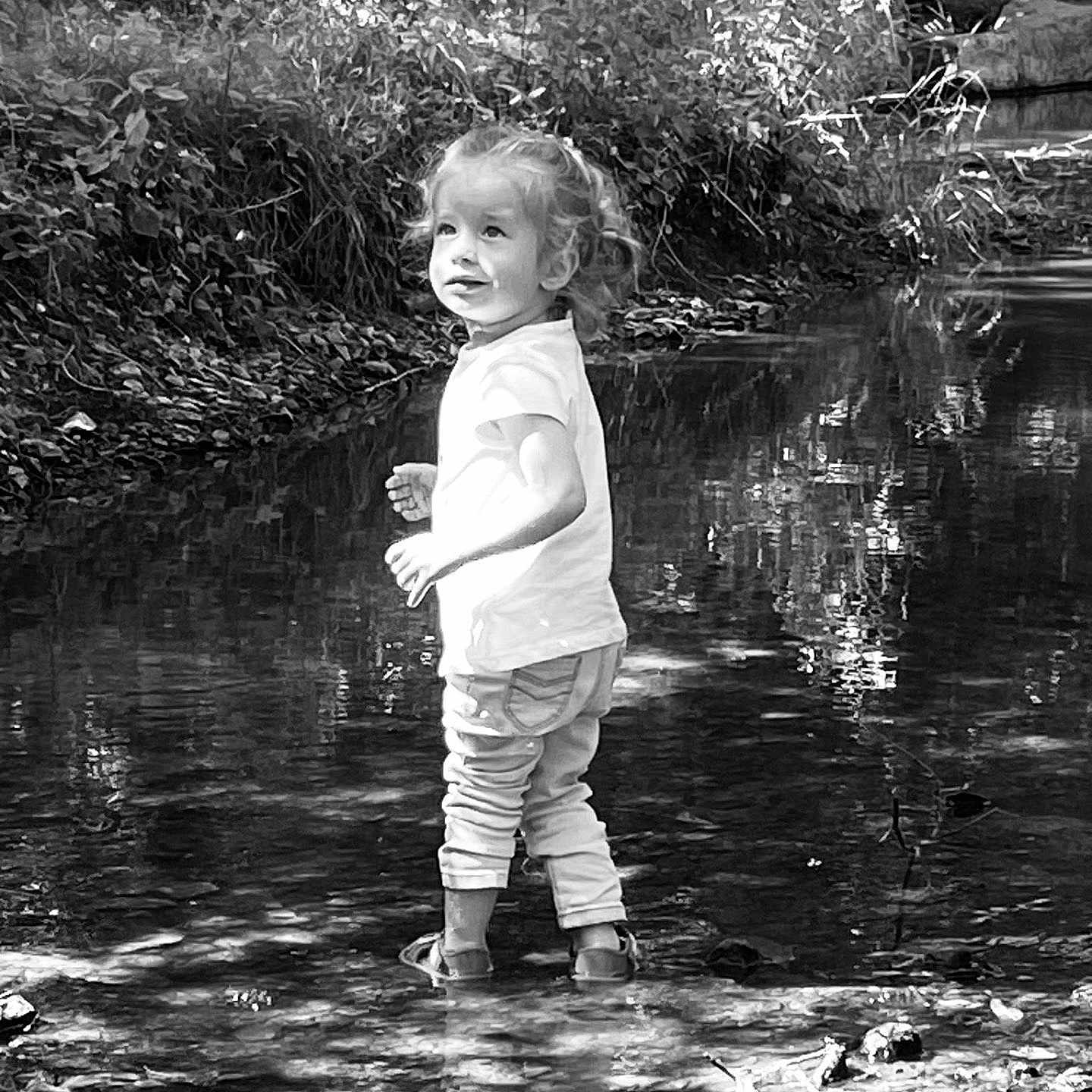 Juliette a rejoint le concours — aidez-le/la à gagner de superbes lots ! black_and_white, child, creek, curly_hair, daylight, forest, nature, outdoor, pants, plants, playful, reflection, rocks, shirt, shoes, smile, standing, toddler, trees, water