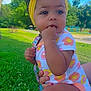 baby, child, outdoor, grass, headband, yellow_bow, onesie, flower_pattern, hand_in_mouth, greenery, sunny_day, park, trees, blue_sky, cute, infant, person, nature, summer, playground