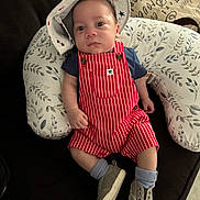 Kaysen joined the competition — help win amazing prizes! baby, infant, hat, romper, striped_clothing, shoes, socks, pillow, couch, patterned, face, person, clothing, indoor, cute, child, seated, footwear, relaxed, young