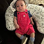 baby, infant, hat, romper, striped_clothing, shoes, socks, pillow, couch, patterned, face, person, clothing, indoor, cute, child, seated, footwear, relaxed, young