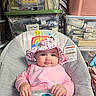 Ellieana is registered to the contest to win money with this photo: baby, infant, child, portrait, smiling, floral_hat, pink_clothing, bib, sitting, baby_seat, face, hands, indoors, storage_bins, laundry, towels, fabric, organized, household, colorful