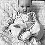 baby, infant, child, blanket, pajamas, clothing, face, person, sitting, indoor, cute, soft, texture, monochrome, black_and_white, portrait, young, expression, cozy, comfort