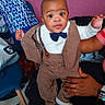 Marcus a rejoint le concours — aidez-le/la à gagner de superbes lots ! adult_hand, baby, bow_tie, chair, child, cute, hands, indoors, infant, pants, patterned_pillow, pillow, portrait, ring, smile, socks, suit, suspenders, wide_eyes, wristwatch