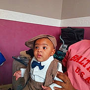 Marcus participe au concours pour gagner de l'argent avec cette photo : adult_hand, baby, bag, bow_tie, child, cuteness, fashion, flat_cap, hands, infant, portrait, room_corner, shirt, smiling, sofa, suit, vest, wall_trim, watch, wide_eyes