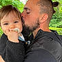 Aerys participe au concours pour gagner de l'argent avec cette photo : affection, baby, beard, black_sweater, child, close_up, face, family, greenery, happy, head_shot, holding, kiss, man, nature, outdoor, pacifier, person, portrait, tattoo