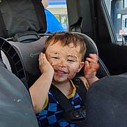 Courtlan is registered to the contest to win money with this photo: toddler, child, car_seat, chocolate, messy_face, smile, happy, car_interior, seatbelt, blue_clothing, hands, window, gas_station, cup_holder, vehicle, portrait, young_child, playful, indoors, seat