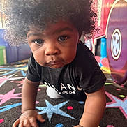 Logan joined the competition — help win amazing prizes! toddler, child, afro_hair, crawling, carpet, colorful, playroom, indoor, curious, black_clothing, hands, face, eyes, expression, floor, toy, pattern, young_child, person, portrait
