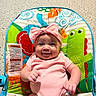 baby, infant, smiling, pink_clothing, headband, baby_chair, colorful, animal_print, indoor, happy, child, cute, playful, seated, person, portrait, young_child, furniture, toddler, bright