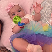 Vida joined the competition — help win amazing prizes! baby, child, infant, portrait, lying_down, pink_pillow, flower_headband, rainbow_dress, tulle_skirt, baby_toy, rattle, smiling, face, eyes, indoor, bed, blanket, colorful, pastel, photography