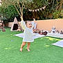 toddler, child, grass, outdoor, garden, teddy_bear, toy, blanket, play_area, smile, happy, sunlight, decorations, party_hat, tree, tent, cushion, barefoot, person, celebration