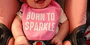 Madison is registered to the contest to win money with this photo: baby, smiling, car_seat, pink, headband, bib, clothing, infant, child, cute, happy, footwear, sitting, indoor, person, face, young_child, accessory, seat_belt, toy