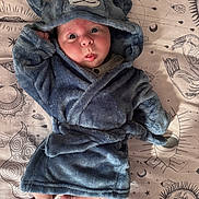 Sebastian is registered to the contest to win money with this photo: baby, infant, blue_robe, plush, cute, surprised_expression, lying_down, feet, face, hood, animal_ears, blanket, patterned, celestial, stars, moons, soft_texture, child, portrait, indoor