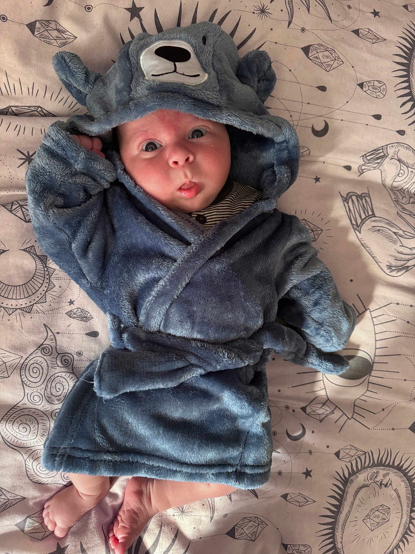 Sebastian is registered to the contest to win money with this photo: baby, infant, blue_robe, plush, cute, surprised_expression, lying_down, feet, face, hood, animal_ears, blanket, patterned, celestial, stars, moons, soft_texture, child, portrait, indoor