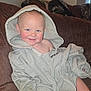 toddler, child, hoodie, smile, couch, remote_control, sunflower, indoor, casual, clothing, happy, face, sitting, home, cute, playful, cozy, furniture, young_child, relaxed