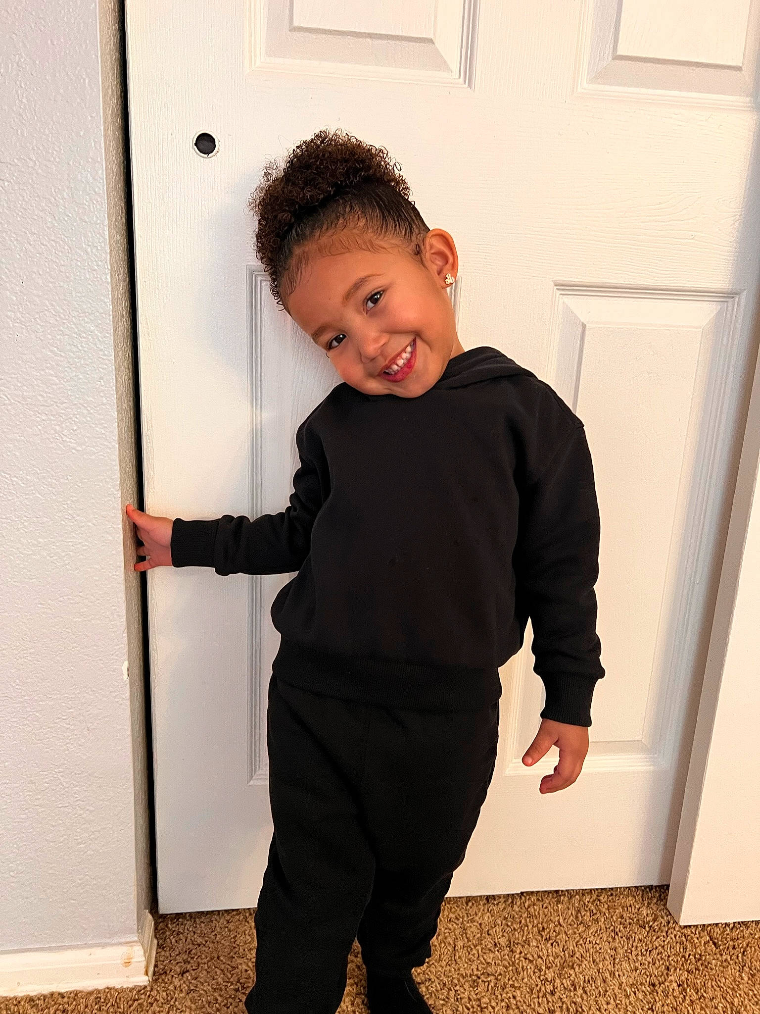 Mila is registered to the contest to win money with this photo: baby_toddler_clothing, collar, door, elbow, flooring, fun, gesture, happy, human_leg, joint, joy, knee, leg, pattern, person, shoulder, sleeve, smile, sweatpant, t_shirt