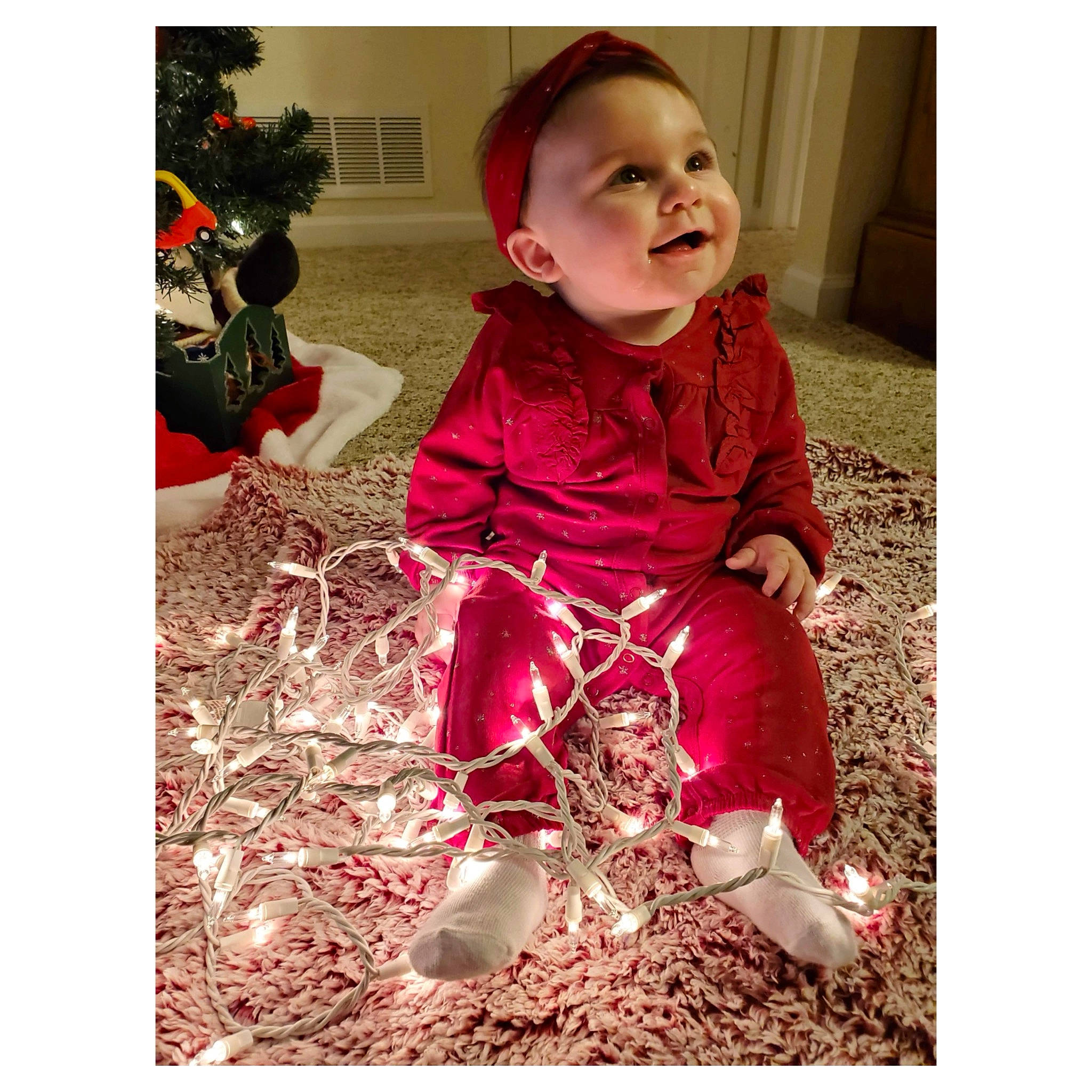 Audree is registered to the contest to win money with this photo: baby, baby_laughing, baby_toddler_clothing, child, christmas, christmas_decoration, christmas_eve, christmas_tree, headwear, holiday, ornament, person, toddler, tongue