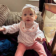 Mia-Louise is registered to the contest to win money with this photo: baby, casual, child, clothing, couch, cozy, curious, fabric, headband, home, indoor, light, person, pink_pants, playpen, sitting, smiling, toddler, toy, window