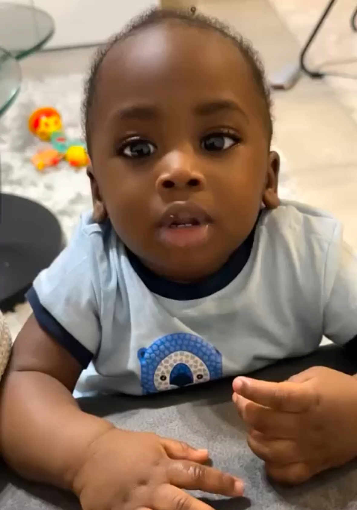 Mathys participe au concours pour gagner de l'argent avec cette photo : baby, child, indoor, curious, blue_shirt, hands, face, eyes, toy, floor, soft_surface, infant, person, cute, expression, young_child, casual_clothing, portrait, closeup, home