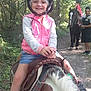 child, helmet, pony, horse, forest, trail, smile, outdoor, nature, person, animal, riding, happy, adventure, casual_clothing, daylight, greenery, footpath, adult, sneakers