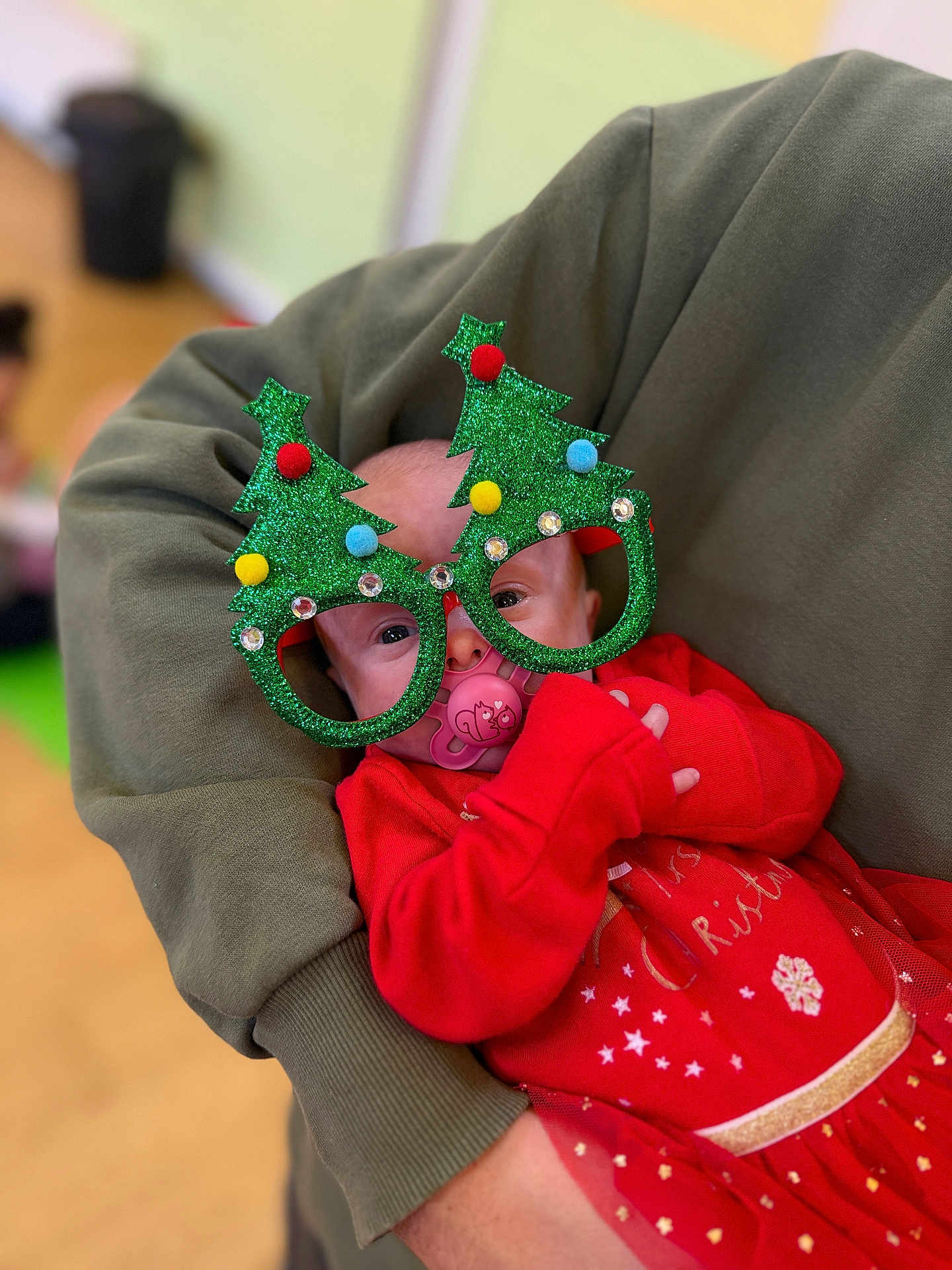 Bonnie joined the competition — help win amazing prizes! baby, child, glasses, christmas, holiday, red_clothing, pacifier, green_glasses, sparkle, festive, cute, person, holding, adult_arm, indoor, celebration, smile, funny, costume, face