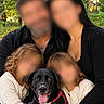 family, children, adults, dog, puppy, black_dog, pet, portrait, group_photo, outdoor, forest, trees, autumn, cuddling, smiling, tongue_out, harness, sweaters, necklaces, nature