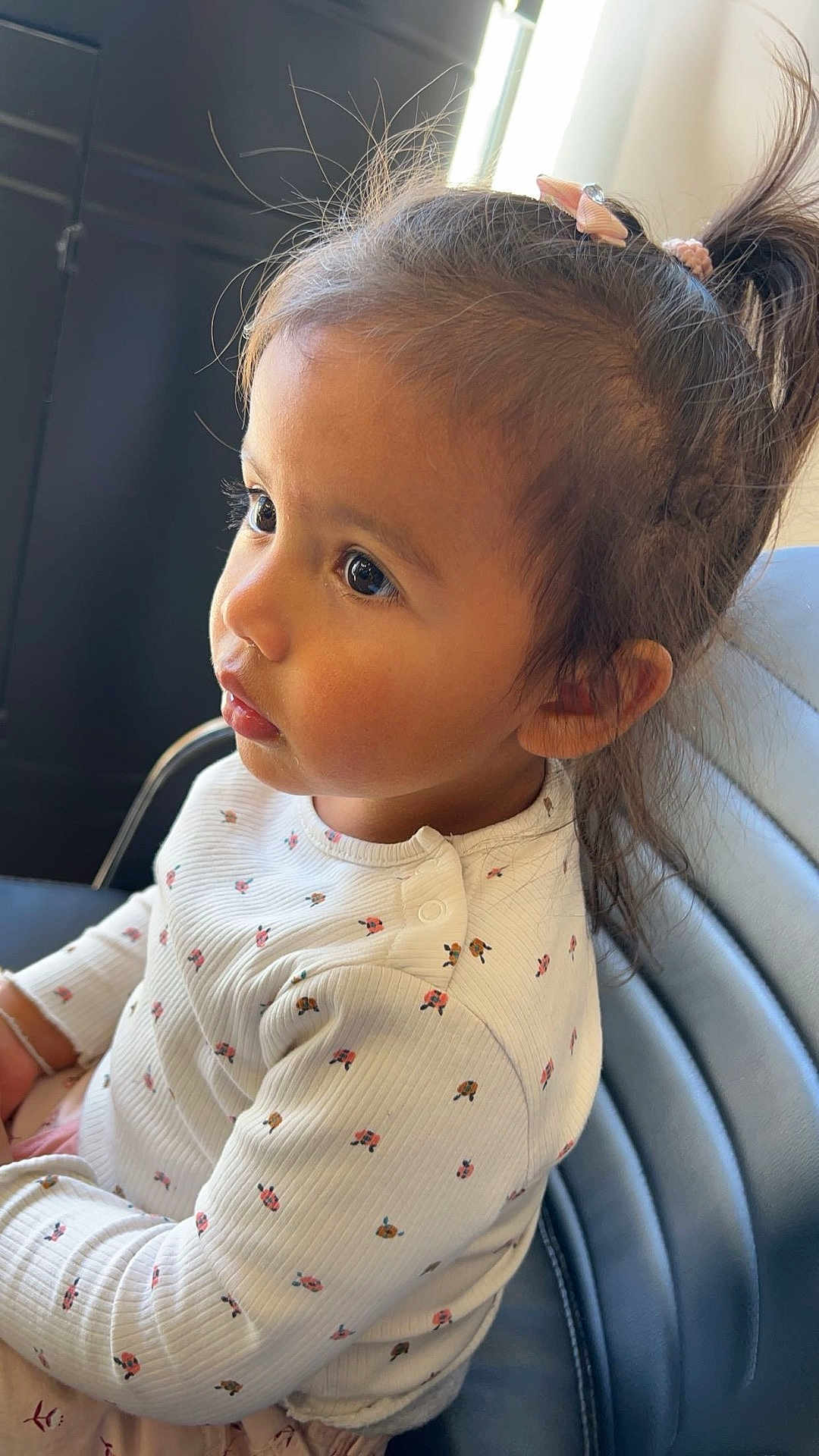 Phraya Soa participe au concours pour gagner de l'argent avec cette photo : toddler, child, girl, portrait, indoor, curly_hair, bow, long_hair, white_shirt, patterned_clothing, seated, blue_chair, side_profile, cute, young_child, focused, natural_light, small_hands, casual_clothing, expression