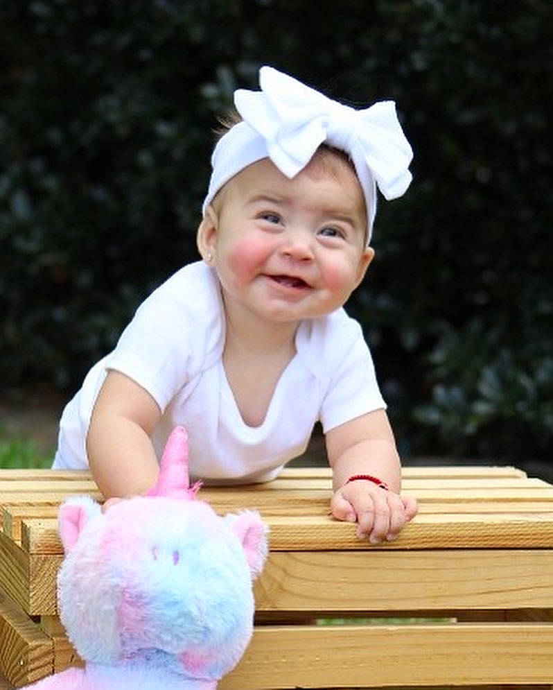 Amani is registered to the contest to win money with this photo: baby, baby_toddler_clothing, cap, cheek, child, facial_expression, flash_photography, fun, grass, happy, hat, headwear, joy, person, pink, sitting, skin, sleeve, smile, toddler