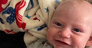 Kyle joined the competition — help win amazing prizes! baby, blanket, child, closeup, comfortable, cozy, cute, face, happy, indoor, infant, lying_down, onesie, patterned_clothing, person, portrait, sleepwear, smiling, soft_texture, warm