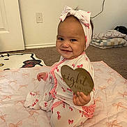 Mari joined the competition — help win amazing prizes! baby, child, infant, smiling, sitting, headband, bow, blanket, sign, heart, milestone, indoors, carpet, cute, clothing, pink, pattern, person, portrait, happy