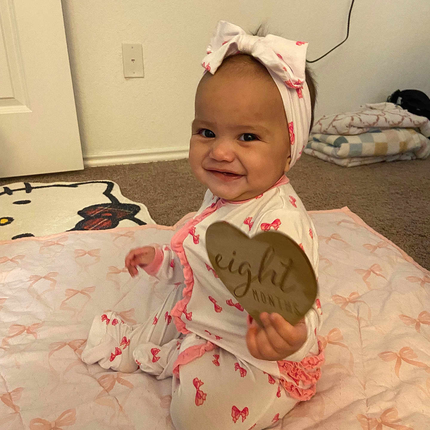 Mari joined the competition — help win amazing prizes! baby, child, infant, smiling, sitting, headband, bow, blanket, sign, heart, milestone, indoors, carpet, cute, clothing, pink, pattern, person, portrait, happy