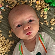Grayson is registered to the contest to win money with this photo: baby, background, bow_tie_print, celebration, cereal, closeup, clothing, colorful, curious, expression, face, food, green_shamrocks, holiday, infant, lying_down, portrait, puckered_lips, texture, white_shirt