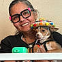 accessories, animal, black_shirt, casual, colorful, dog, face, glasses, happy, hat, holding, indoor, jewelry, person, pet, portrait, smiling, sombrero, watch, woman