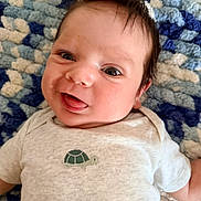 Atlas joined the competition — help win amazing prizes! baby, infant, child, smiling, happy, portrait, face, eyes, hair, wild_hair, lying_down, white_shirt, turtle, clothing, blanket, textured_blanket, indoor, close_up, photography, adorable