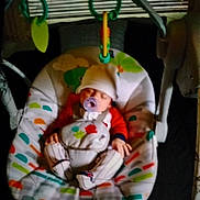 Damon is registered to the contest to win money with this photo: baby, baby_accessory, baby_swing, child, colorful, cozy, cute, hat, indoor, infant, napping, pacifier, patterned_fabric, peaceful, resting, sleeping, small_hands, soft_lighting, toy, wearing_clothes