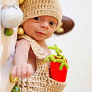 Mahé a rejoint le concours — aidez-le/la à gagner de superbes lots ! baby, infant, knitted_clothing, hat, carrot, toy, chocolate, wrapped_candy, cute, portrait, lying_down, soft_surface, hand, expression, colorful, closeup, child, indoors, warm, cozy