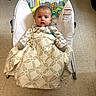 baby, baby_bouncer, blanket, child, clothing, duck, face, giraffe, indoor, infant, jungle_animals, living_room, owl, patterned_blanket, photography, portrait, sitting, swaddled, tiled_floor, wide_eyed