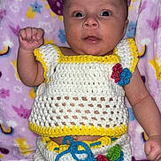 Yolyn joined the competition — help win amazing prizes! baby, infant, crochet_clothing, blanket, patterned_blanket, colorful, hand, face, eyes, expression, cute, lying_down, indoor, soft_texture, knitted, child, newborn, portrait, raised_fist, closeup