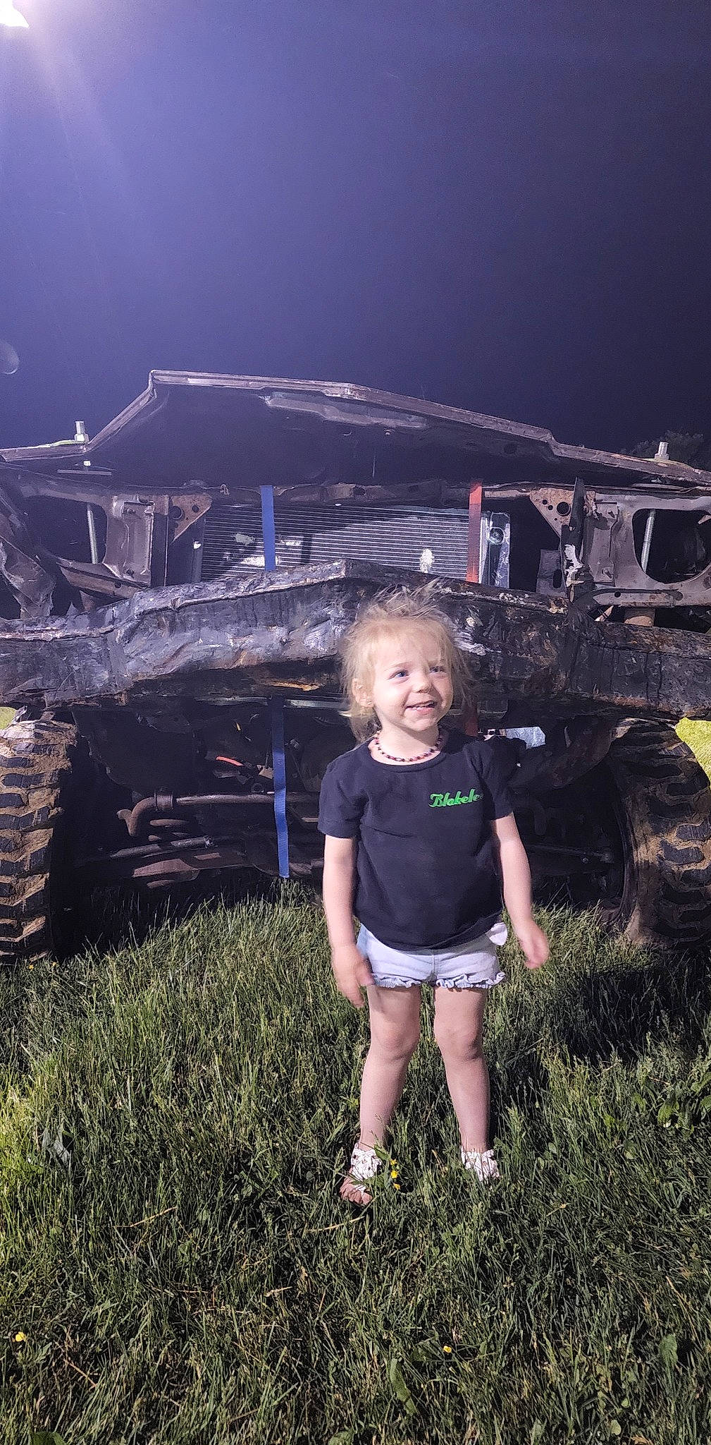Blakelee is registered to the contest to win money with this photo: automotive_lighting, automotive_tire, electric_blue, flash_photography, fun, grass, grassland, happy, joy, landscape, leisure, motor_vehicle, person, plant, shorts, sky, smile, sunlight, t_shirt, tire