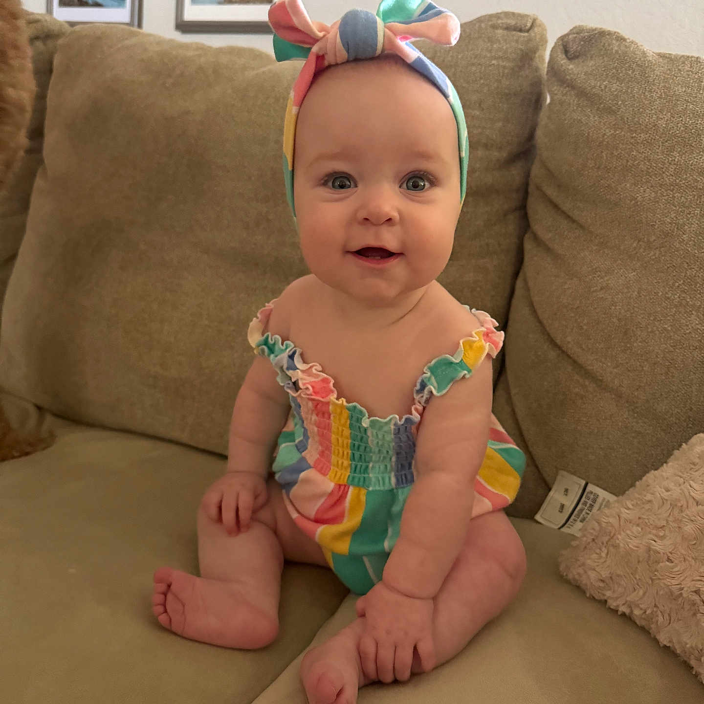 Tully is registered to the contest to win money with this photo: baby, babywear, cheerful, child, colorful_clothing, couch, cushion, cute, furniture, happy, headband, home, indoor, infant, person, portrait, romper, sitting, skin, smiling