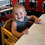 toddler, child, high_chair, smiling, restaurant, table, wooden_chair, indoor, furniture, red_chair, person, casual_clothing, happy, young_child, dining, seat, hair, skin, face, arm