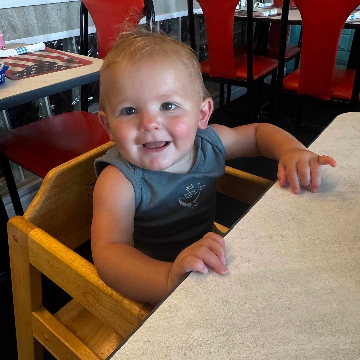 Rocco joined the competition — help win amazing prizes! arm, casual_clothing, child, dining, face, furniture, hair, happy, high_chair, indoor, person, red_chair, restaurant, seat, skin, smiling, table, toddler, wooden_chair, young_child
